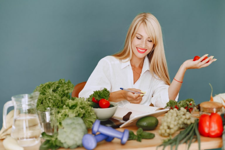 Une femme assise devant beaucoup de légumes verts