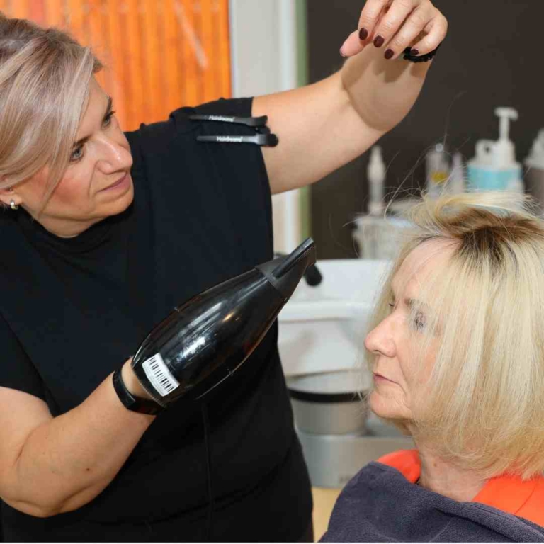 Femme blonde dans un salon partenaire hairdreams se faisant sécher les cheveux