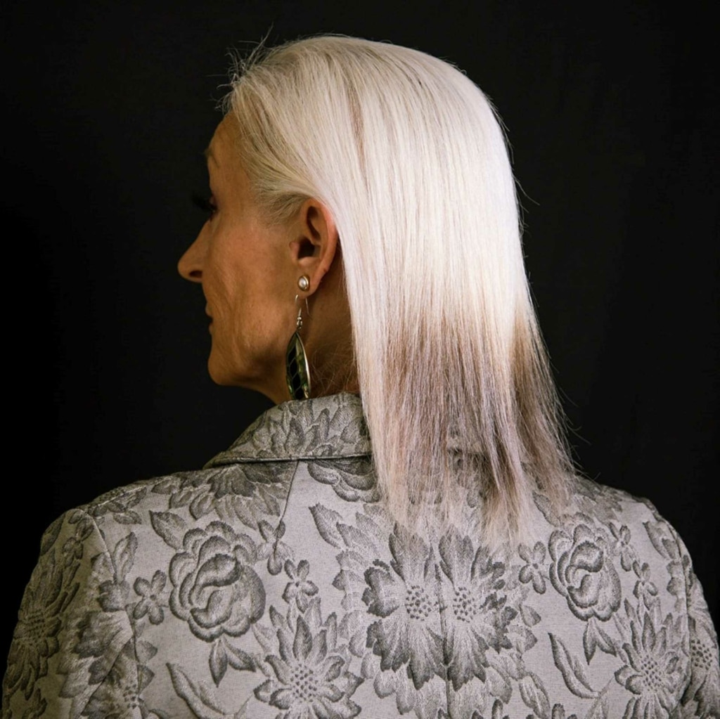 Woman with fine silver-white hair in front of her hair thickener