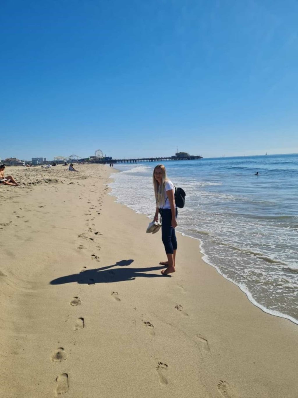 Hairdreams-Mitarbeiterin Mirsada geht barfuß am Strand in Kalifornien.