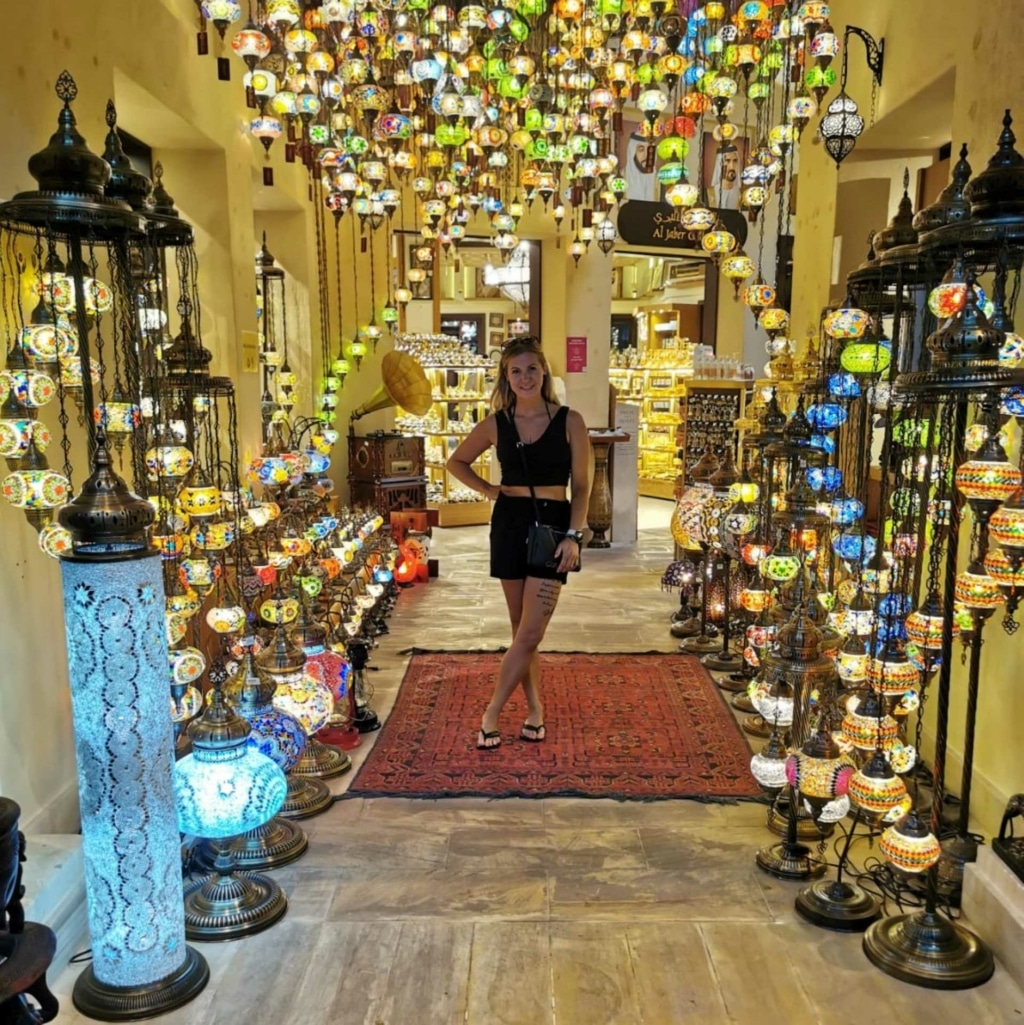 Yvonne, collaboratrice Hairdreams, pose dans un magasin avec de nombreuses lampes colorées à Dubaï.