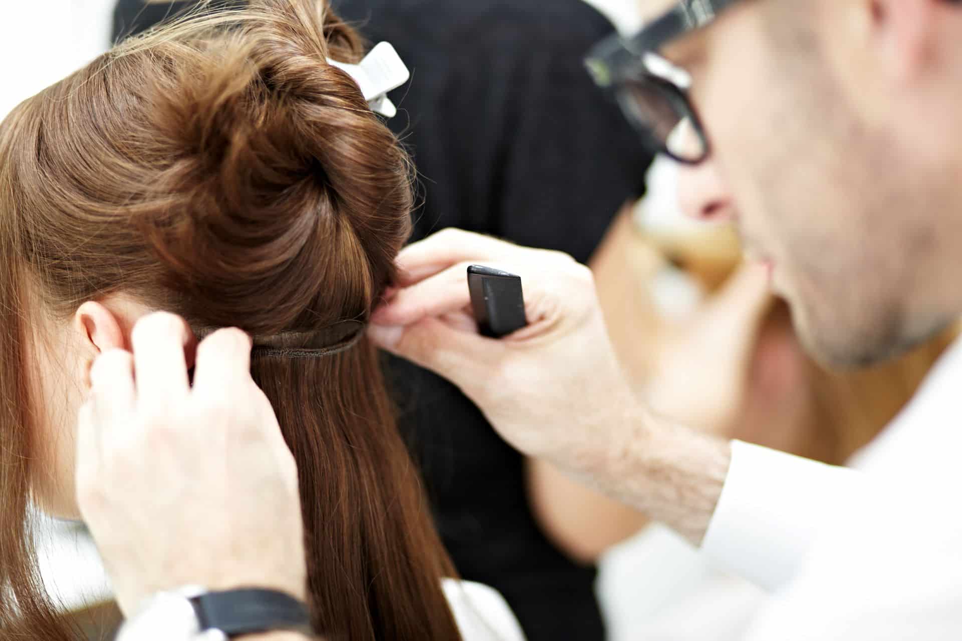 Friseur fixiert die Hairdreams Echthaar-Tressen am Eigenhaar der Kundin.