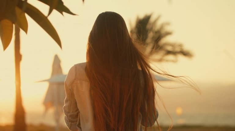 Une femme aux longs cheveux bruns foncés regarde au loin.
