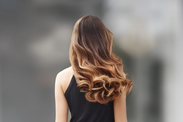 Femme aux cheveux bouclés, portant des Root Shadows Hairdreams, vue de dos
