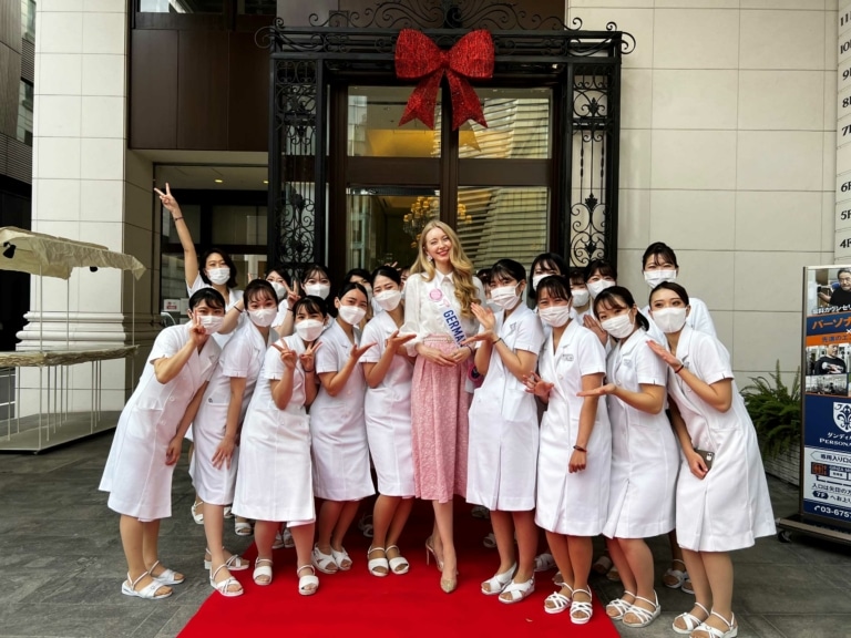 People in white coats stand around Miss International