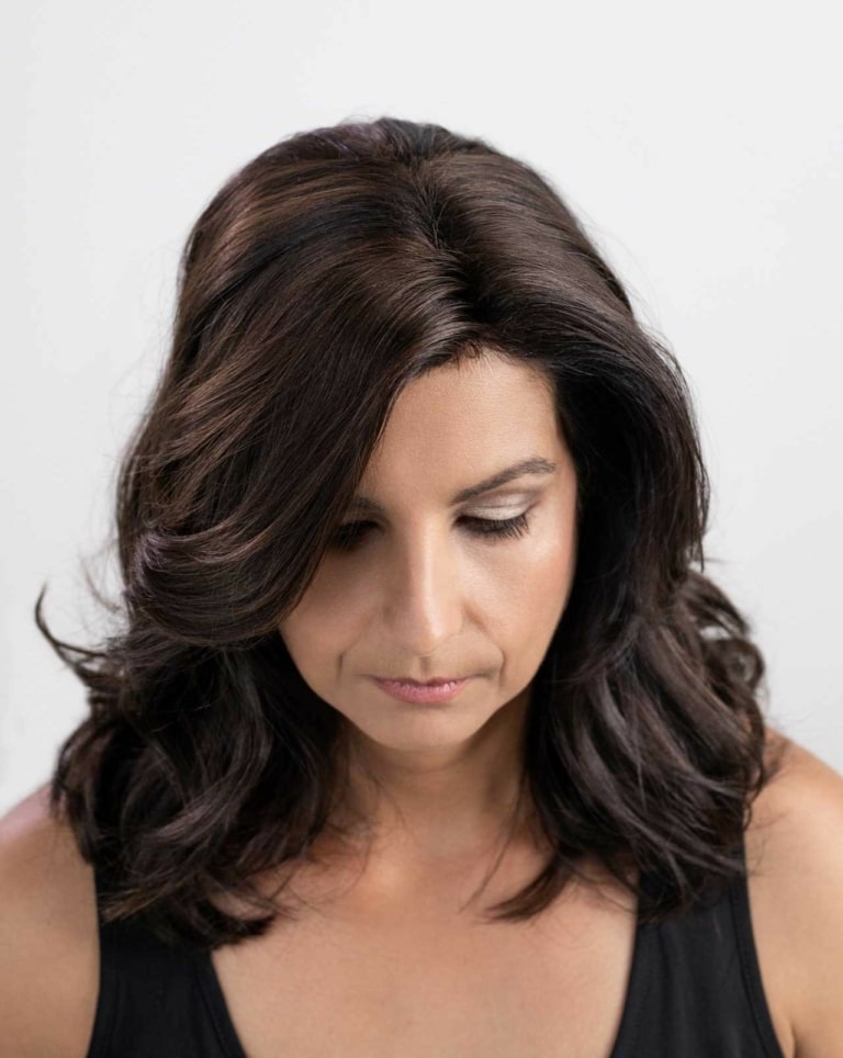 Mujer con cabello negro voluminoso tras el espesamiento capilar con MicroLíneas Hairdreams desde arriba