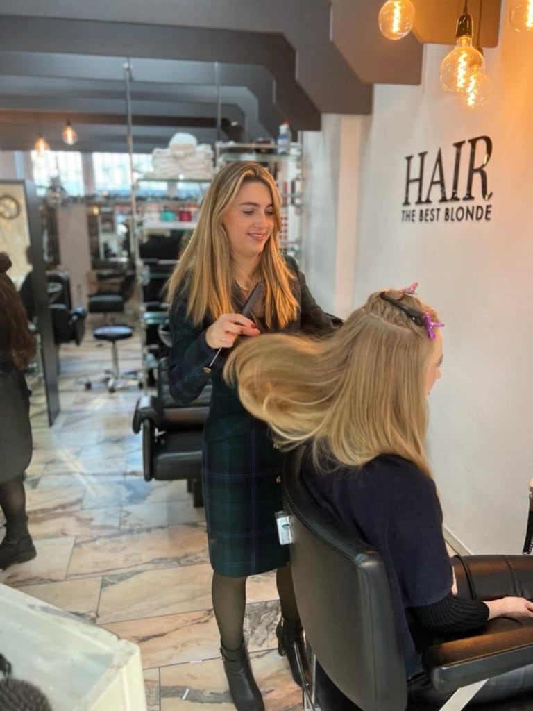 Une coiffeuse d'un salon partenaire Hairdreams pose les extensions de sa cliente